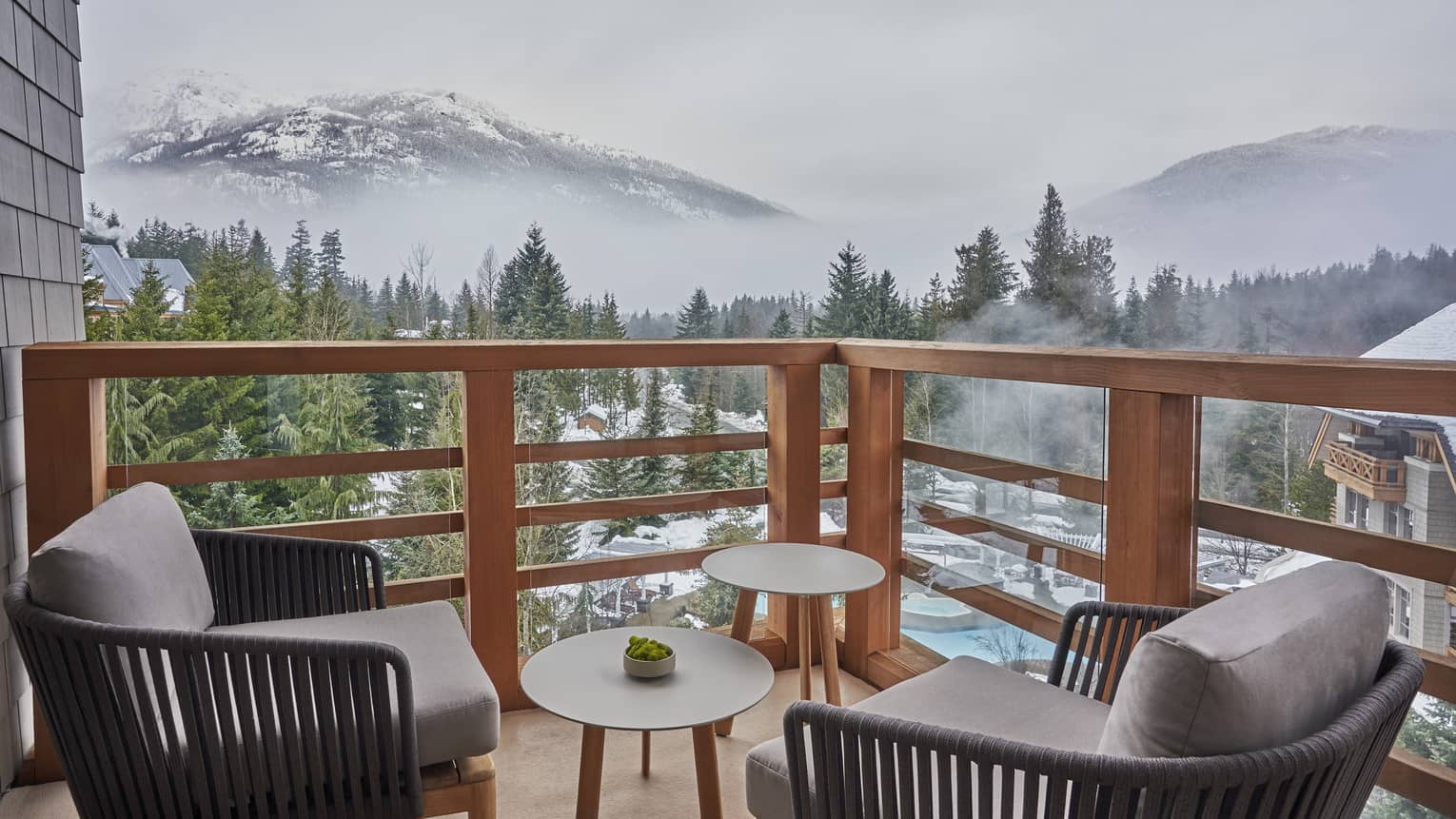 Balcony with two arm chairs and small tables, overlooking Whistler mountains