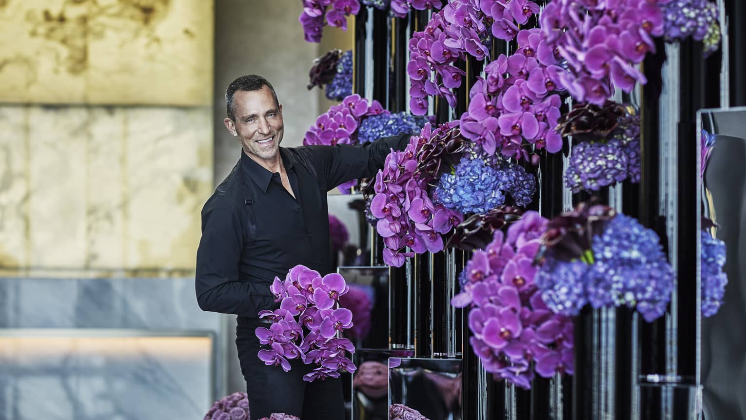 Florist arranges purple and blue flowers in tall black vases