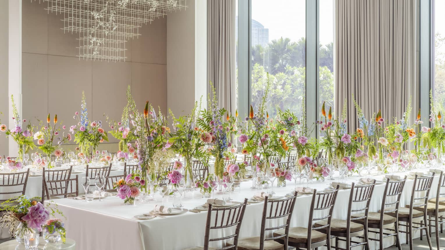 Ballroom set classroom-style with white linen?covered tables and tall floral centrepieces