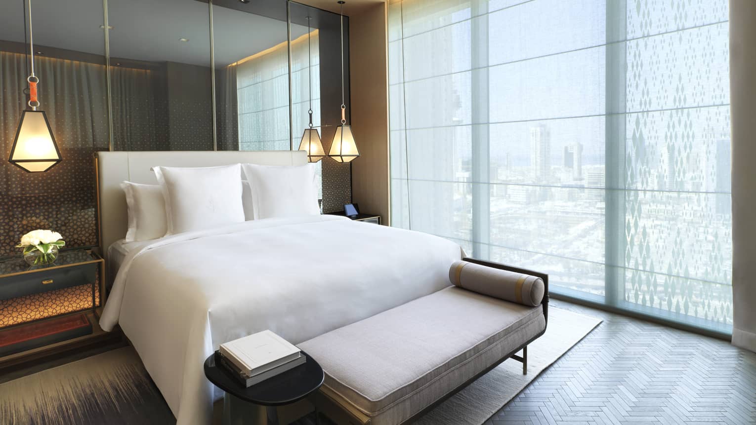 Four Seasons Executive Suite bed in front of mirror wall, hanging lights, beside floor-to-ceiling window