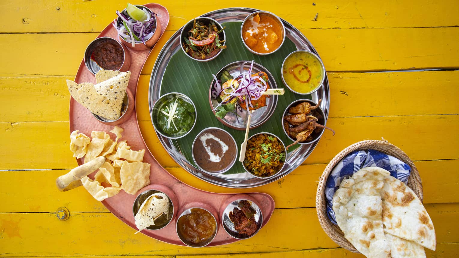An aerial shot of a plate with tortilla chips and colourful sauces on a yellow wooden table at Cafe' Landaa