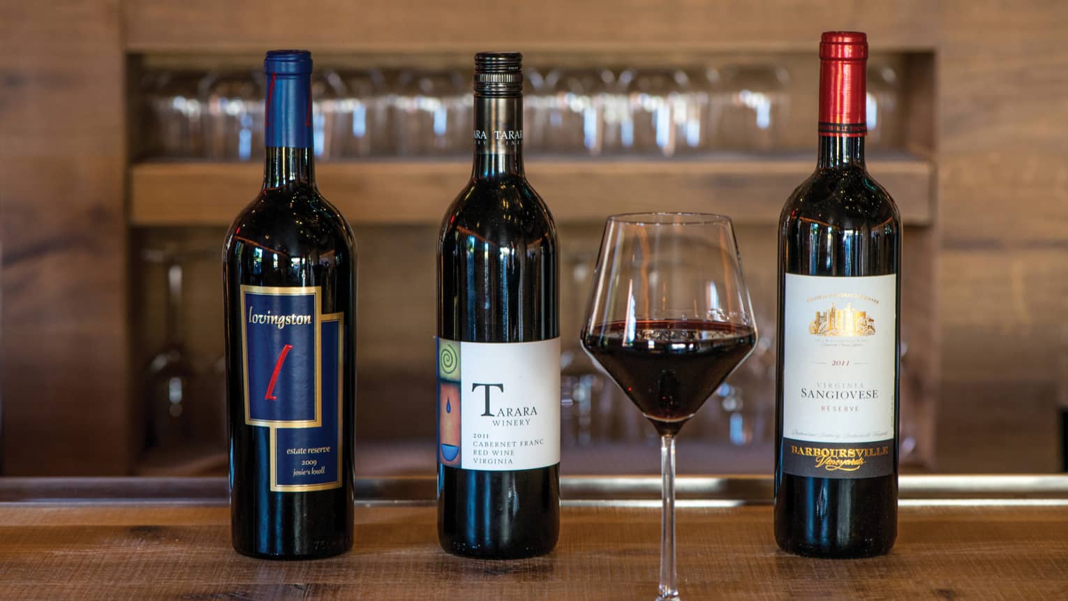 Wine tasting with three bottles of wine, glass of red wine on ENO Wine Bar top