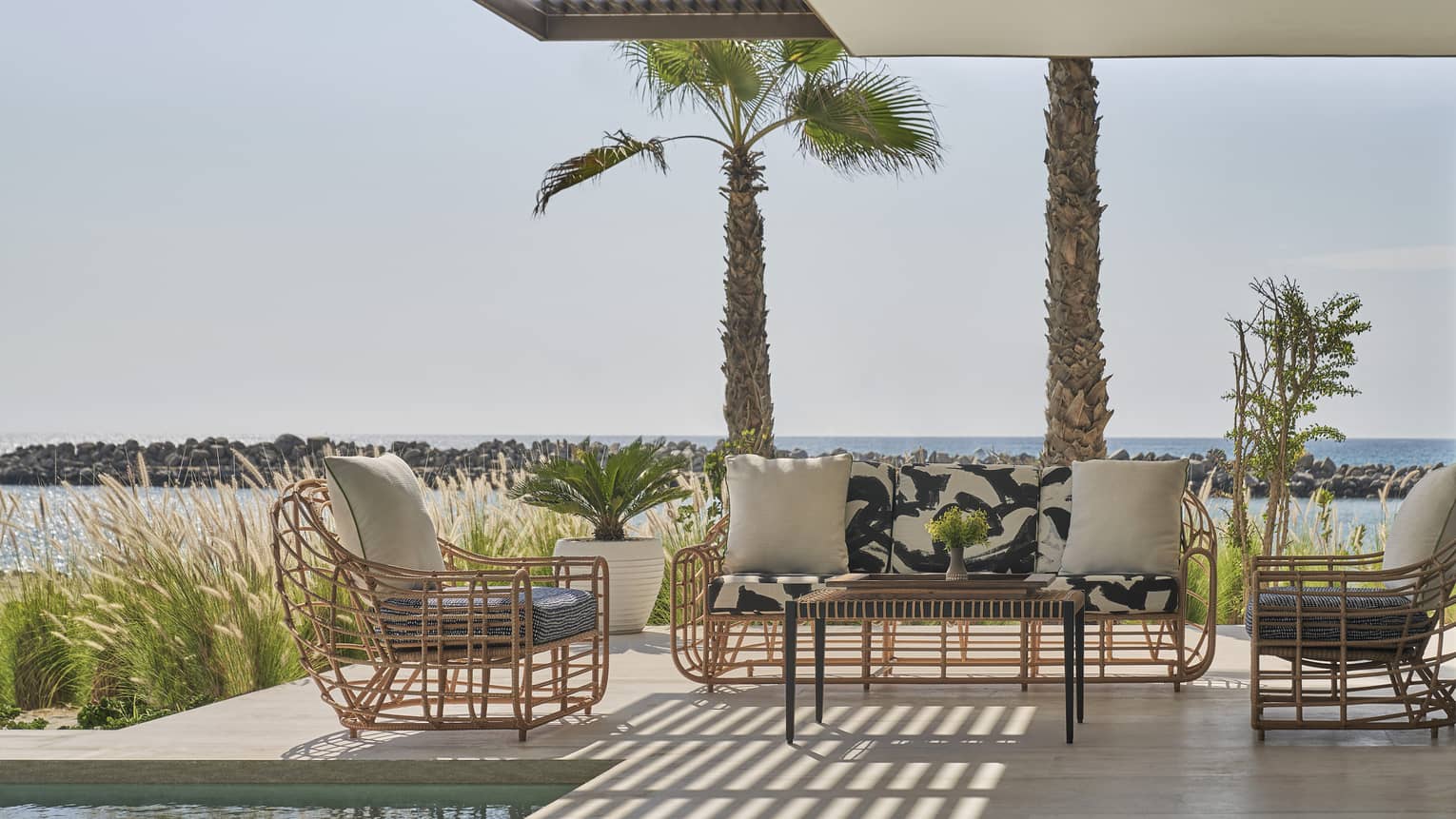 Two Bedroom Sunrise Suite pool, two rattan arm chairs and sofa, palm trees, ocean views