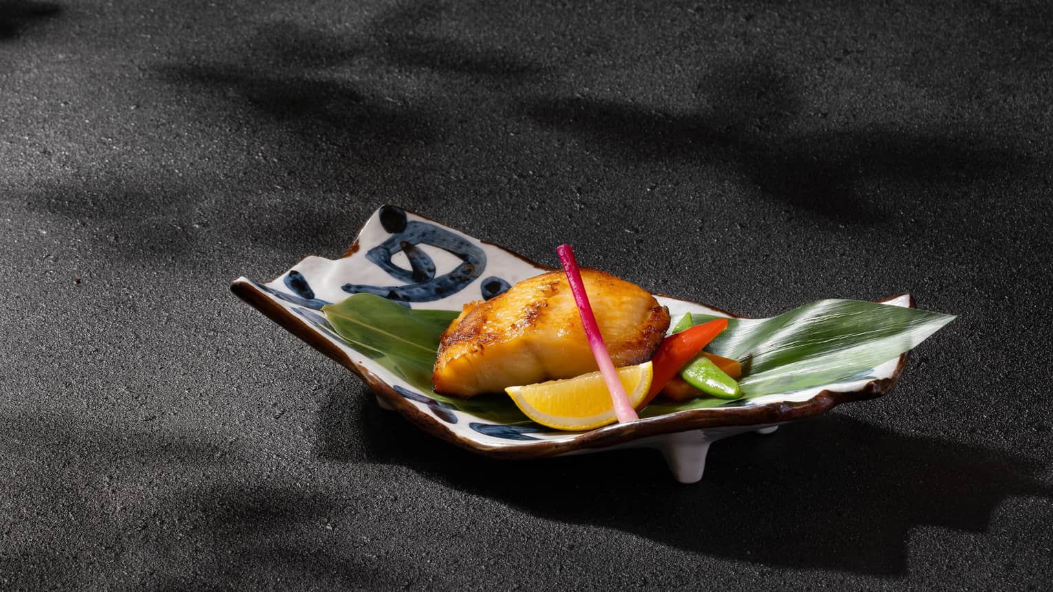 Grilled marinated black cod with miso sauce on banana leaf