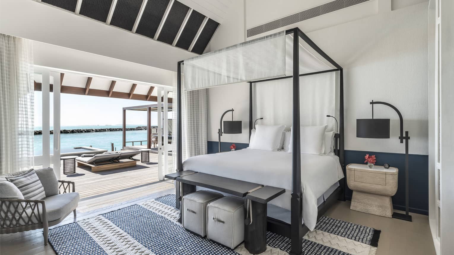Bedroom with four-poster canopied bed with doorway leading to pool deck with cabana