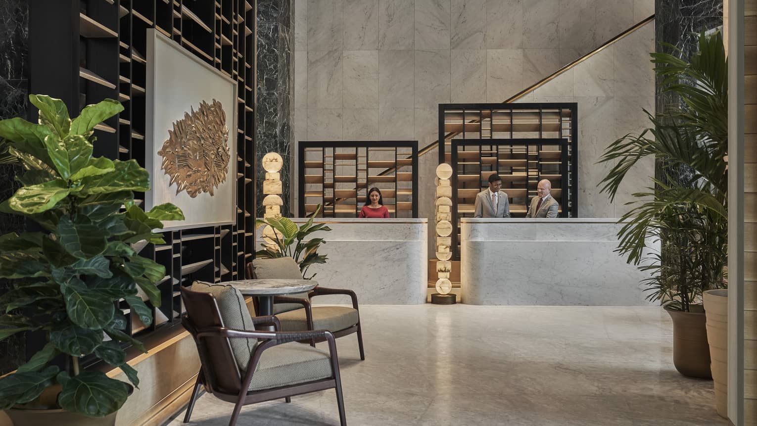 Lobby with double desk, marble floors, sitting area for two and potted palms
