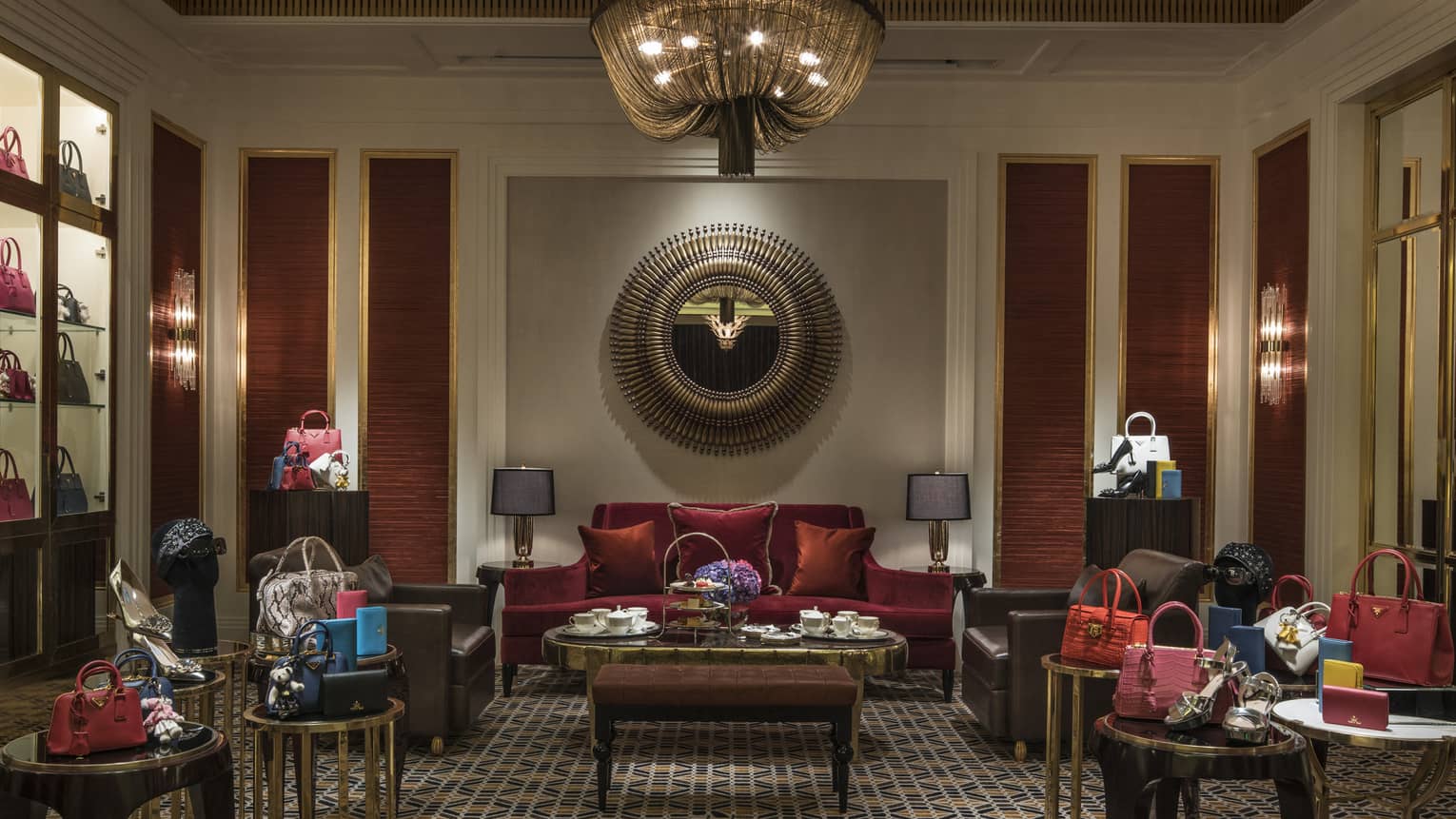 Salon with red velvet sofa, small tables with designer handbags 