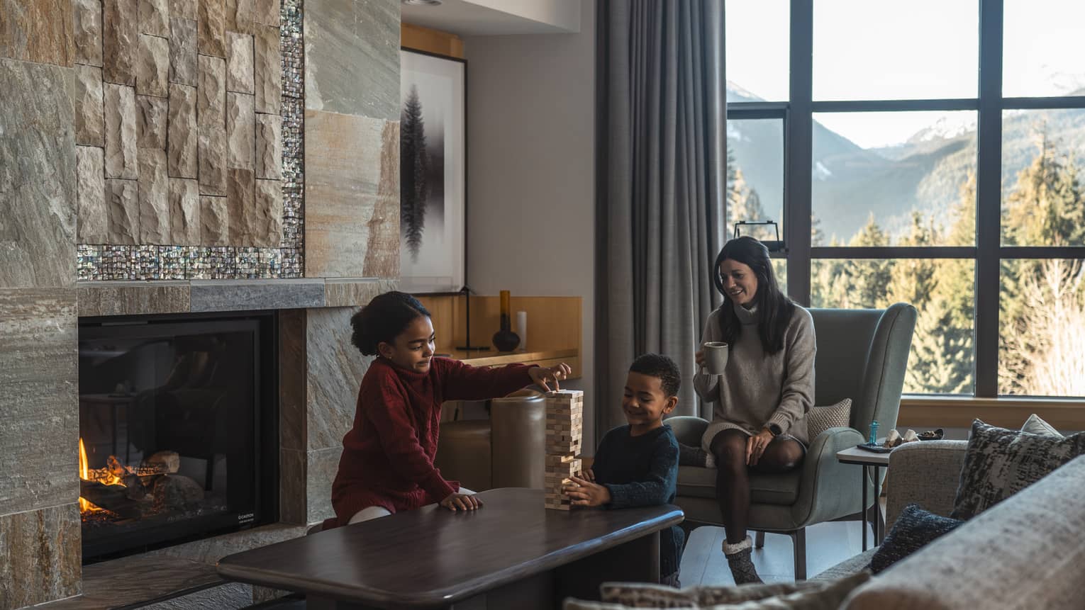 Mother and two children playing Jenga in the living room next to a fireplace