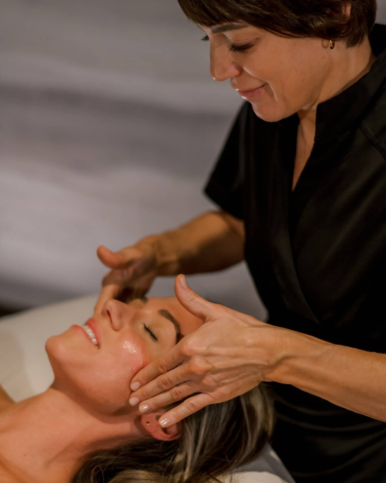 Guest getting a facial massage while laying on massage table.