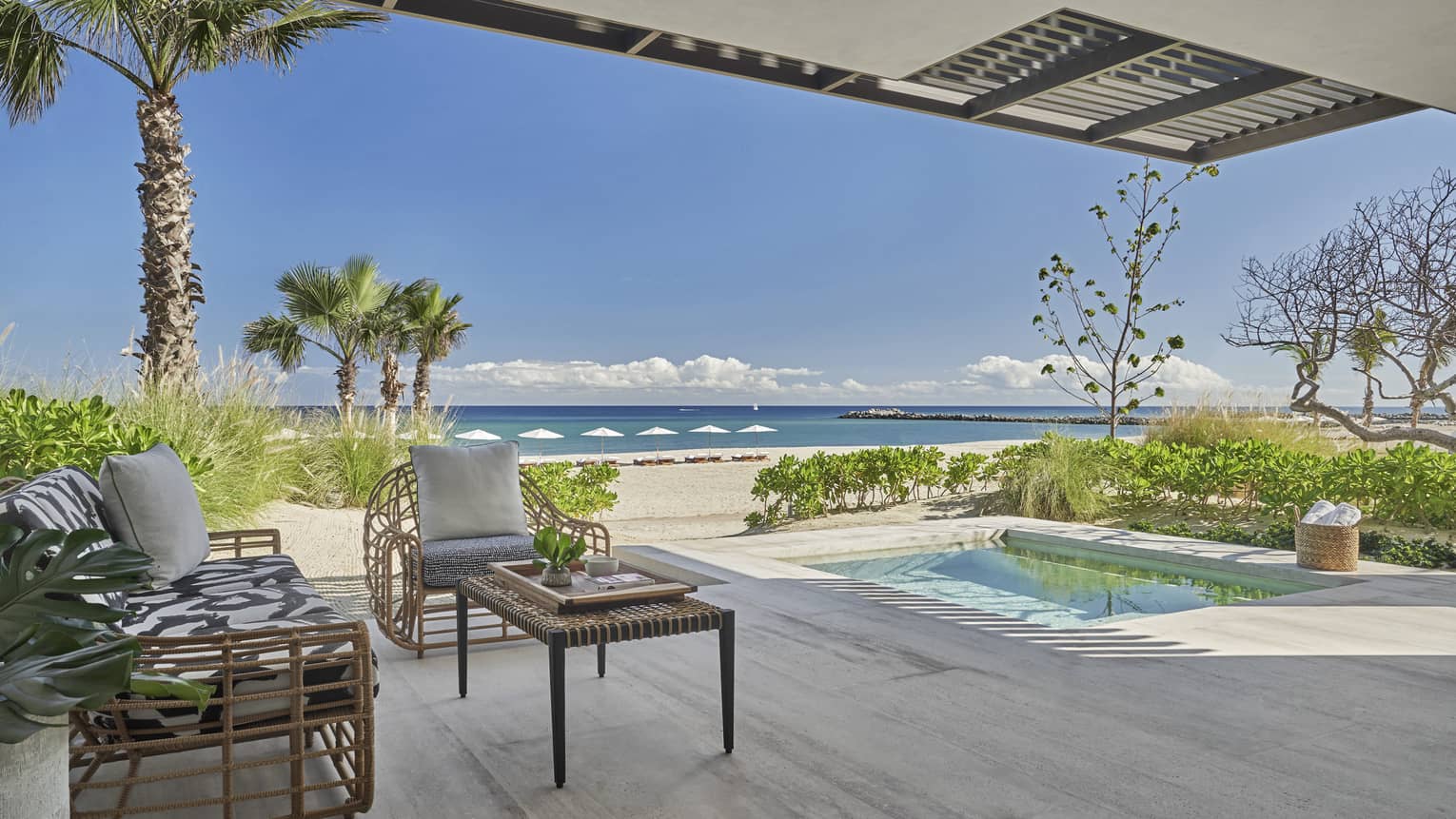 Outdoor terrace with beach and ocean view, small pool, two arm chairs and table