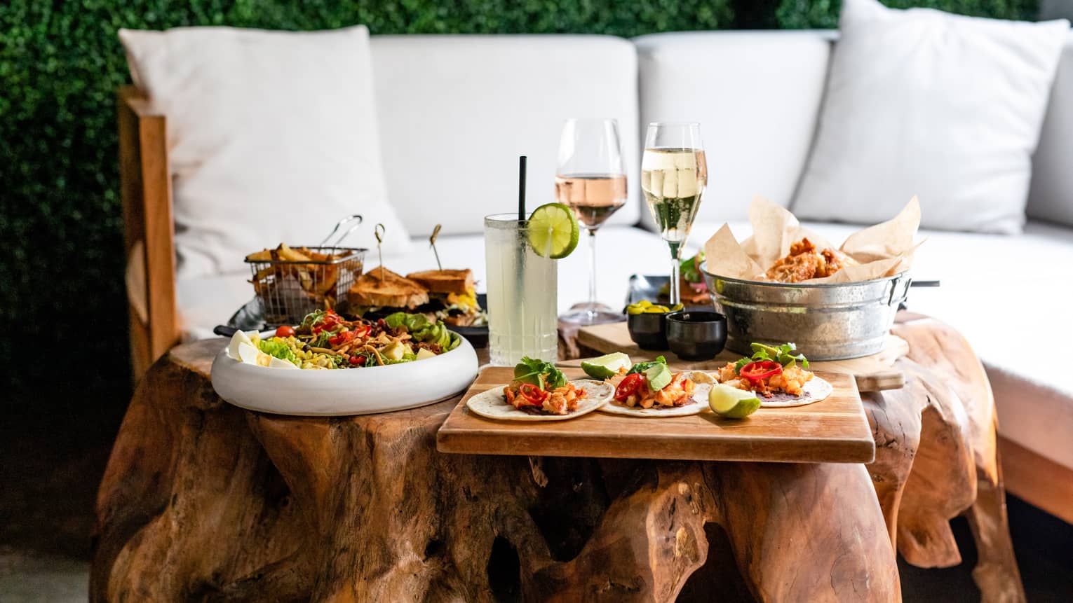 A white and wood sofa outside with various food in front of it.