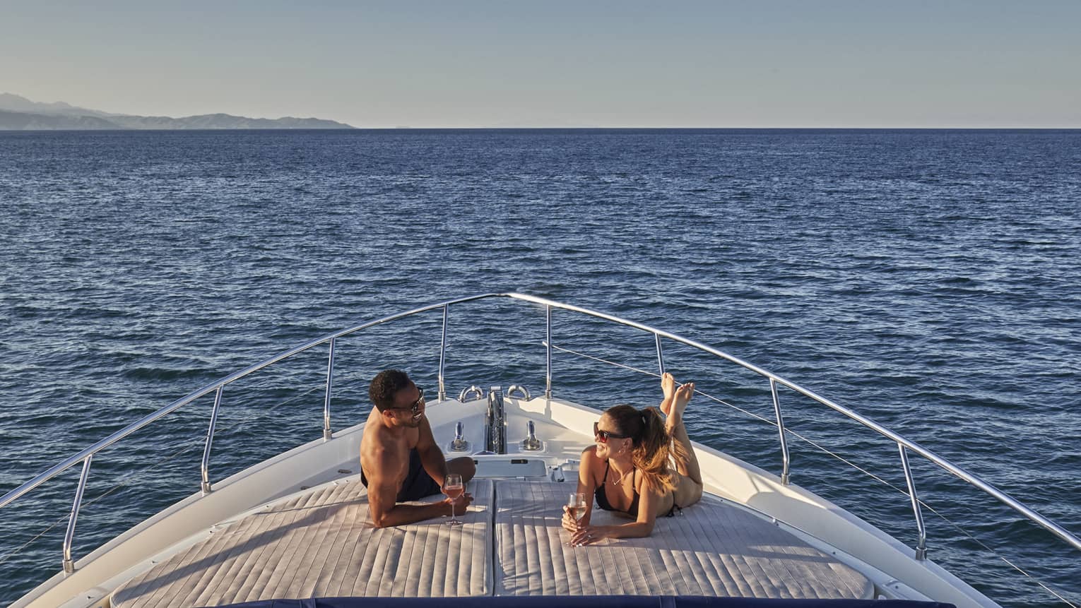 Man and woman lay on front of yacht