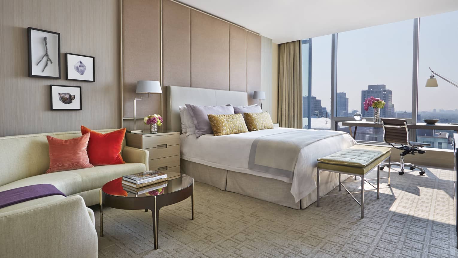 Presidential Suite curved L-shaped sofa with bright pink, orange pillows, bed, desk by sunny window