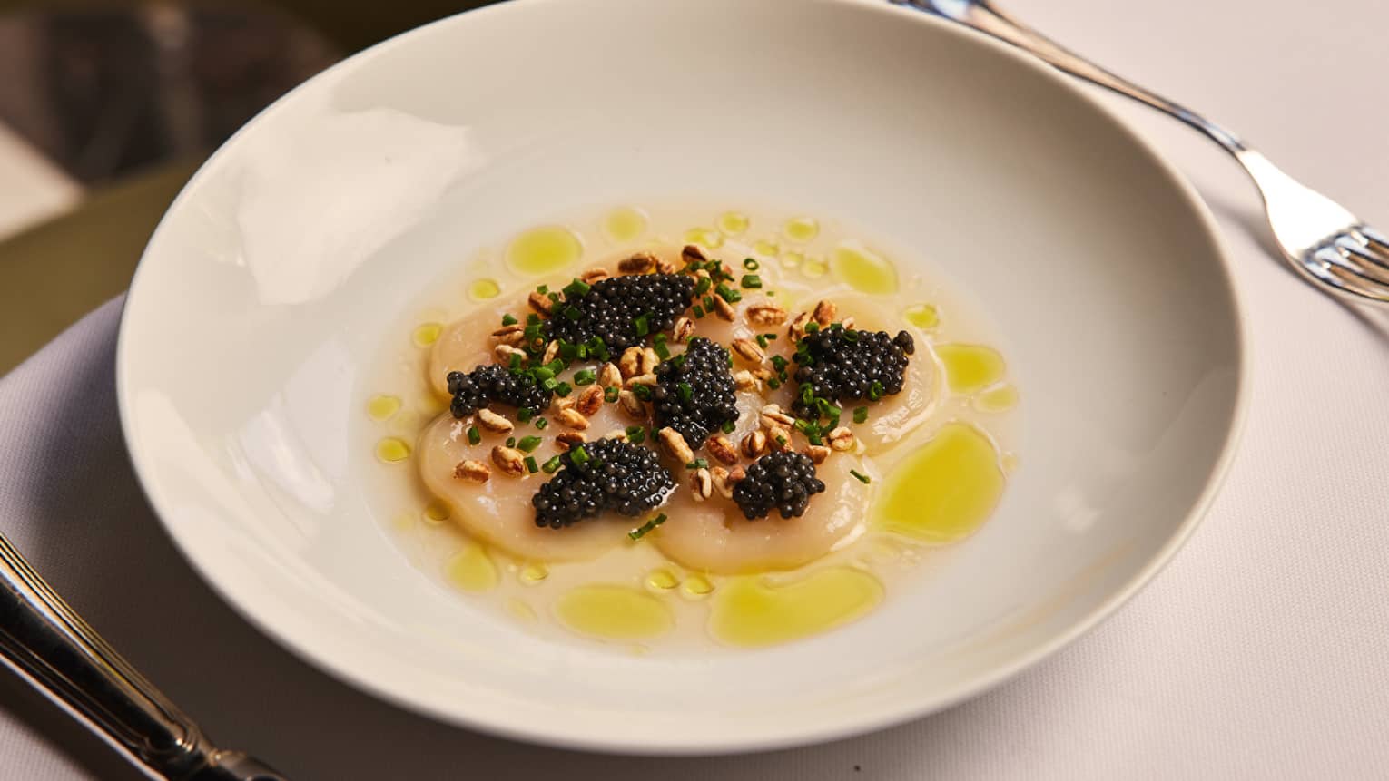 Scallops and caviar on a yellow sauce.