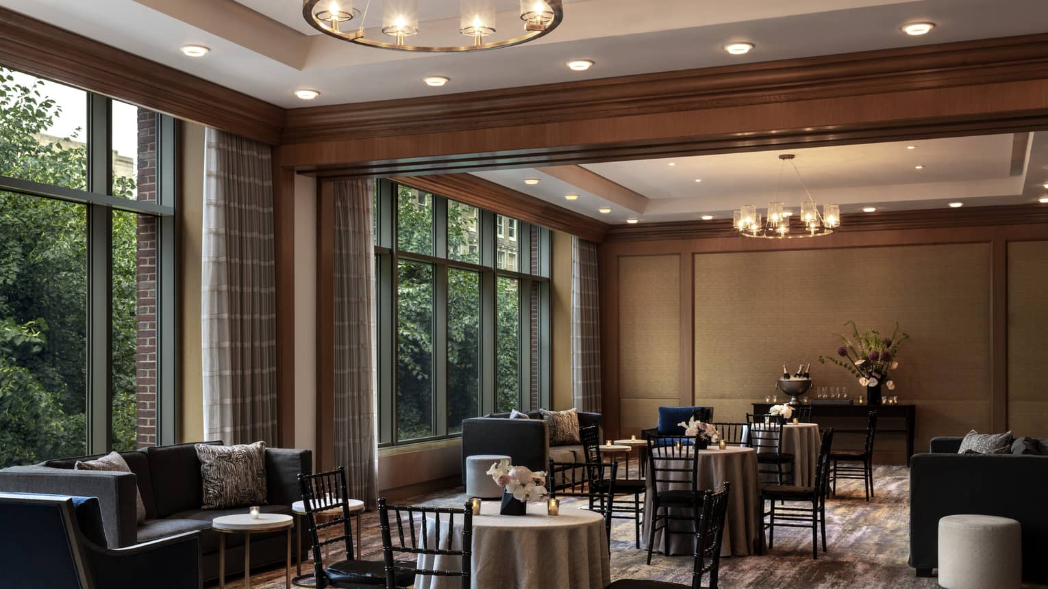 A  dimly lit seating area with black chairs around small tables and small black sofas.