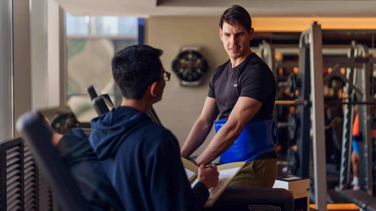 Personal trainer consults with a guest in a hotel gym