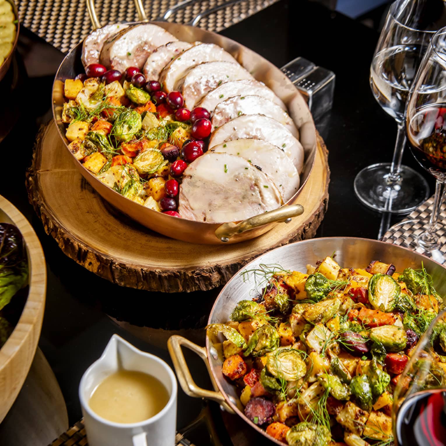 An assortment of food including roasted pork, roasted vegetables, and wine.