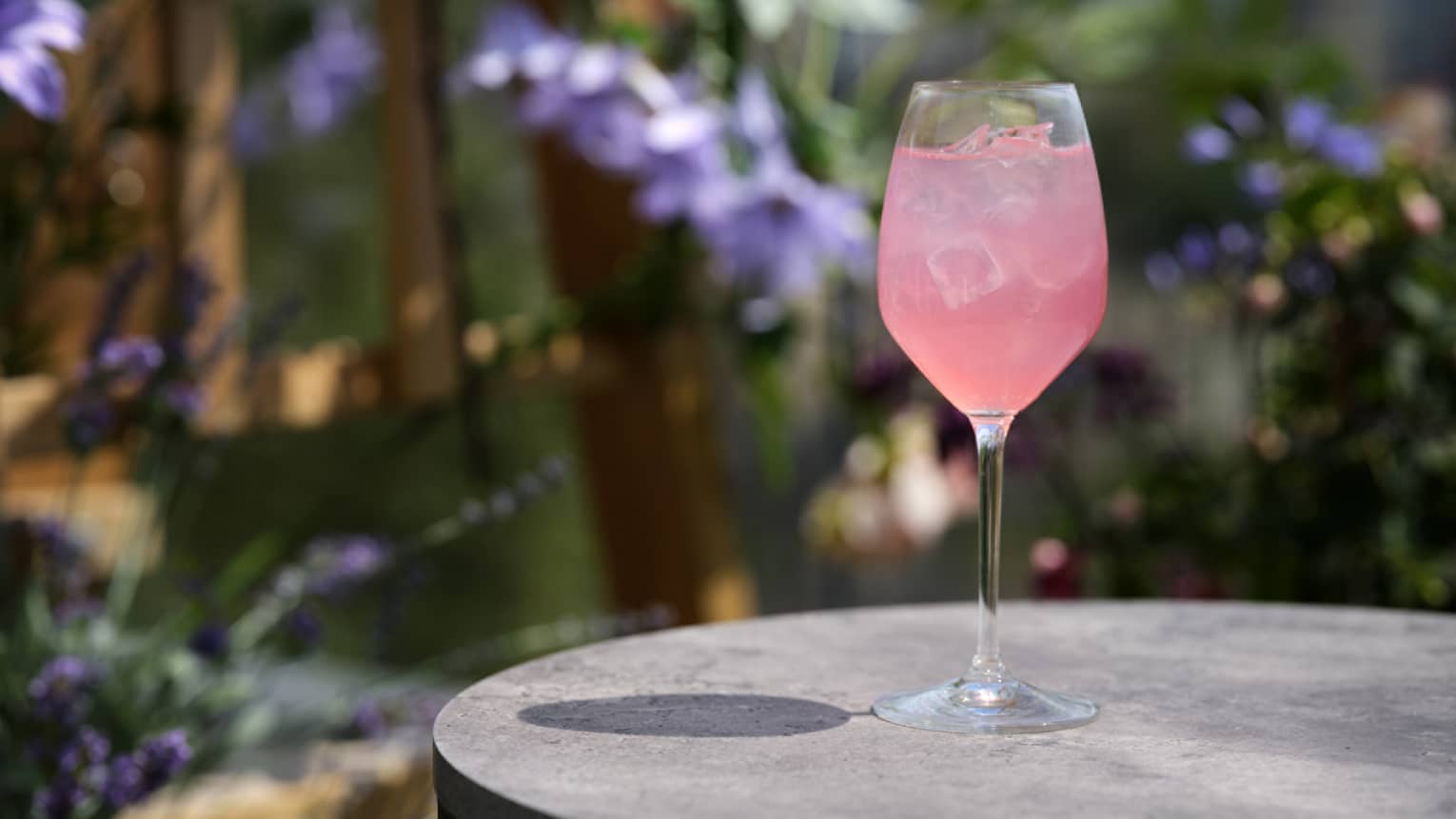 Pale pink cocktail in wine glass on round black table