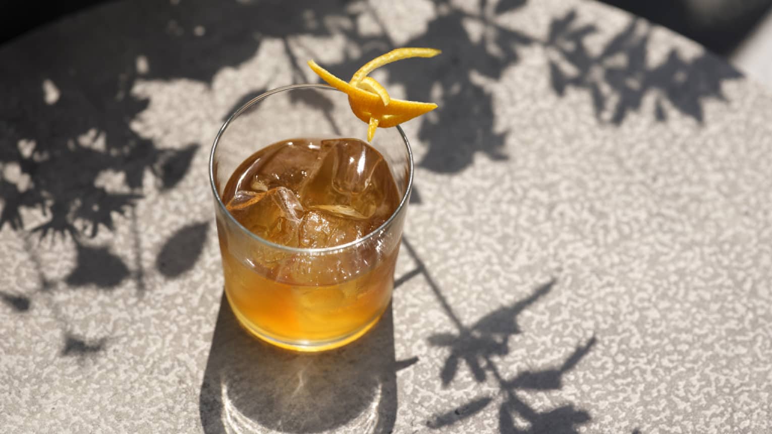 Brown cocktail in old-fashioned glass with orange peel garnish