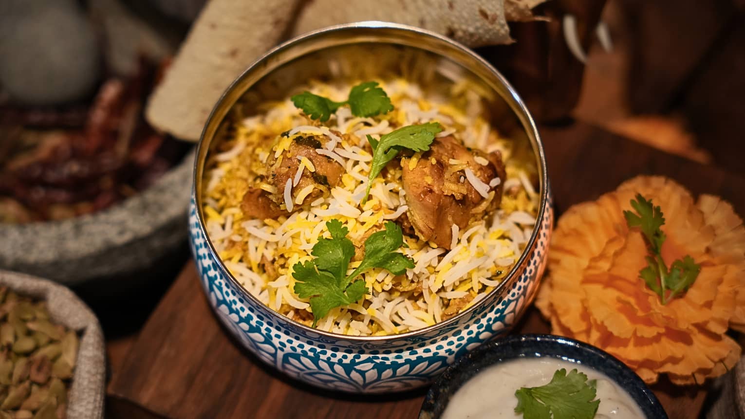 A savoury rice and chicken preparation in a decorative bowl, surrounded by other plates and bowls of food items