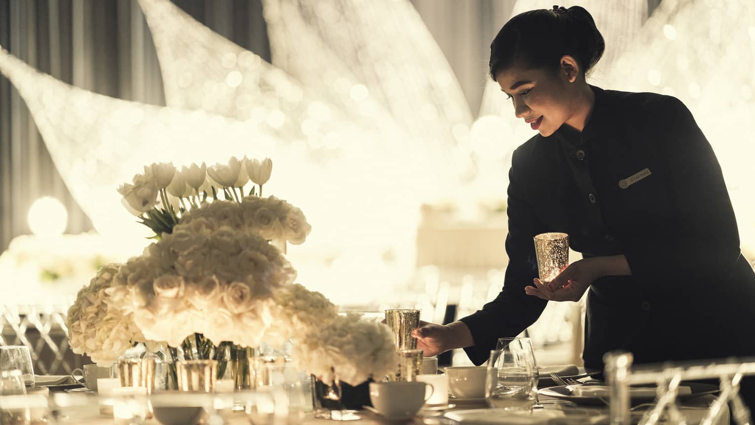 Hotel staff sets gold candle on elegant wedding banquet table