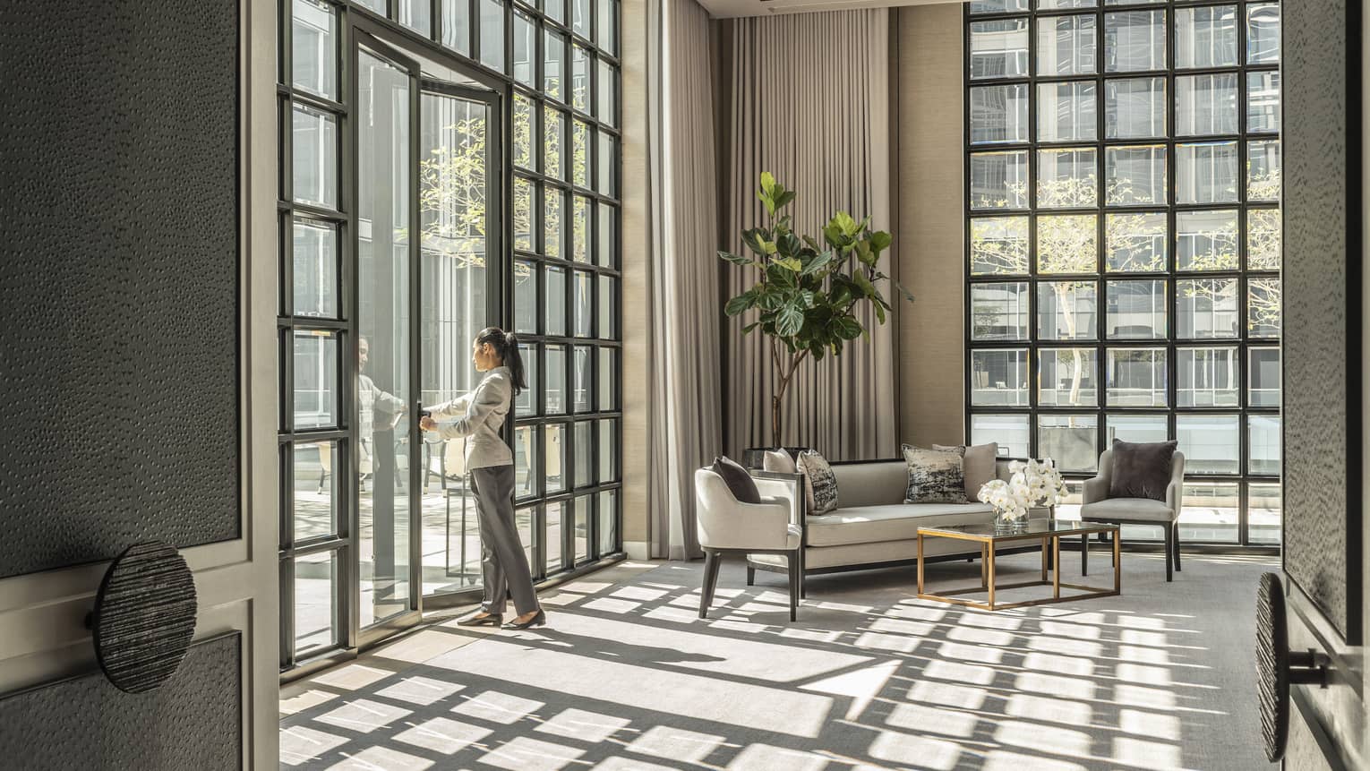 Studio II with cream-coloured carpet and matching furniture, green potted foliage, sunlight streaming in through floor-to-ceiling windows