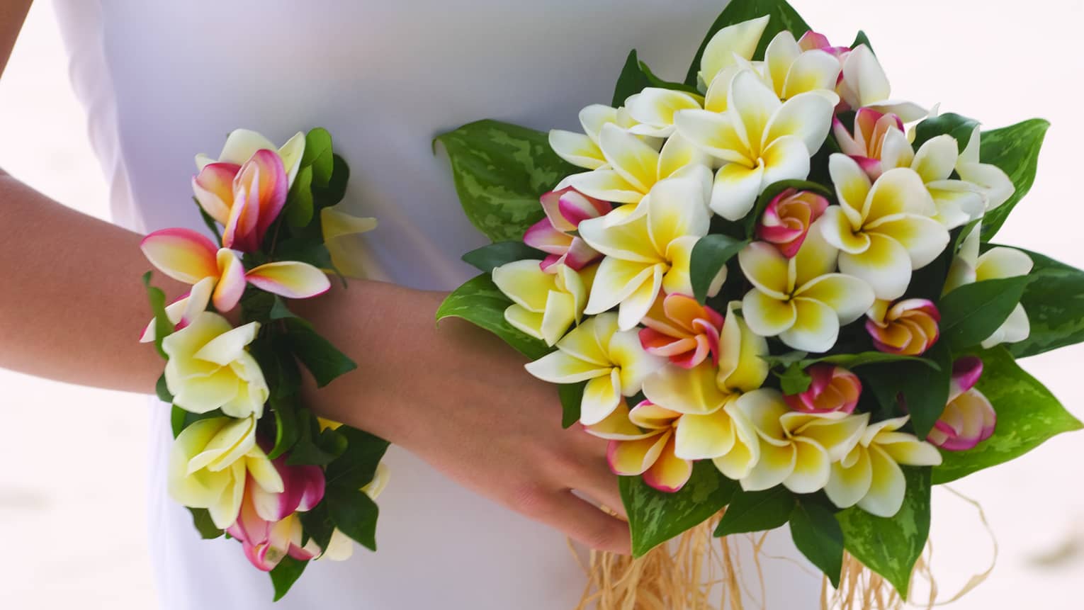 Bride holding wedding bouquet and floral wristband with tropical flowers