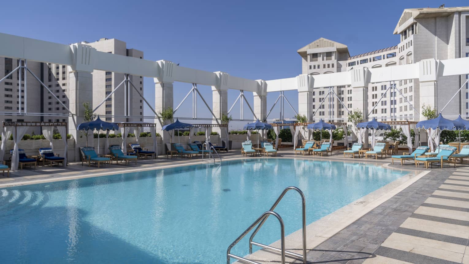 Outdoor pool surrounded by teal lounge chairs and white column