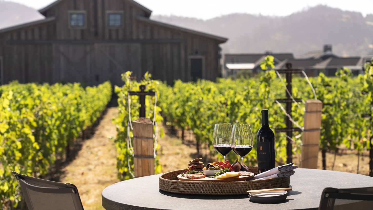 Two wine glasses with a plate of snacks on an outdoor dining table.