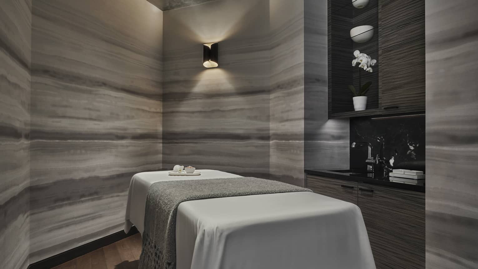 A dimly lit spa room with an empty spa table
