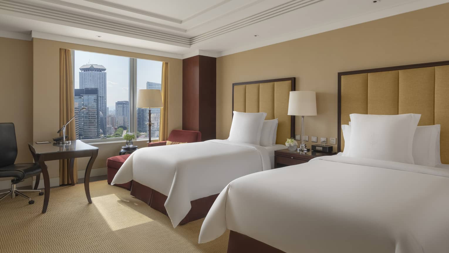 Hotel room with two single beds, leather headboards, table with chair and windowside chaise