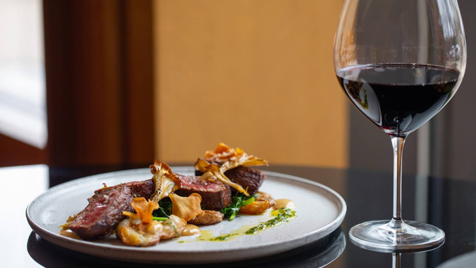 Steak dinner with caramelized chanterelle mushrooms and garlic herb butter, glass of wine