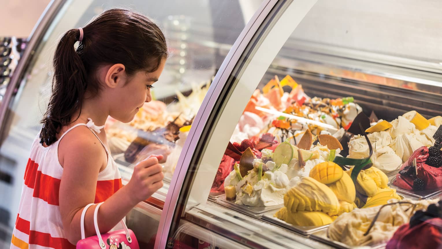 Girl stands at Lickety Split glass counter, looks in at gelato flavours on display