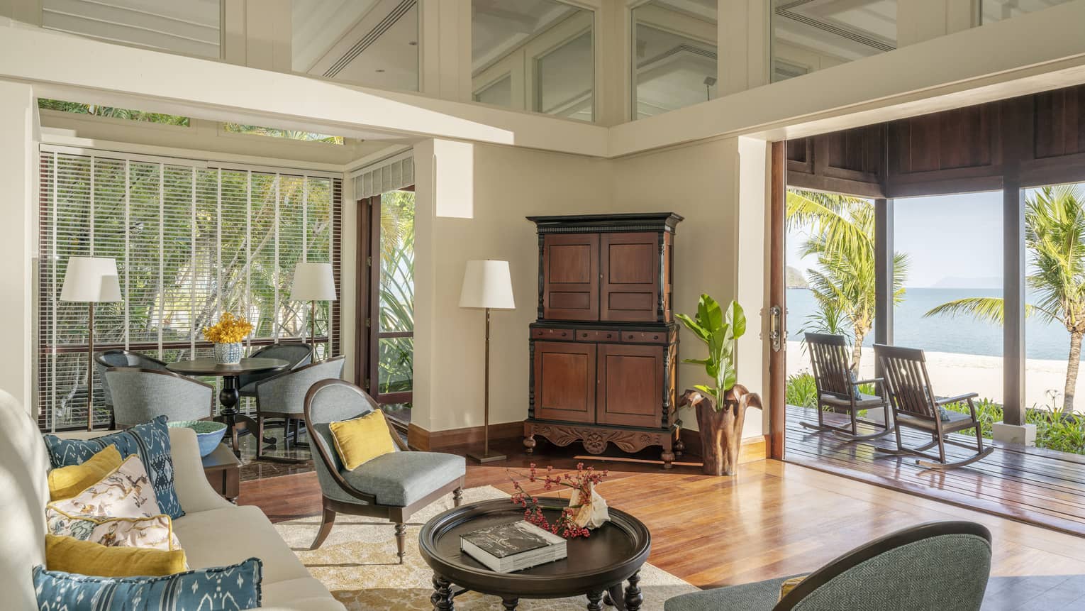 Living room with teak floors and opening to covered terrace looking out to beach