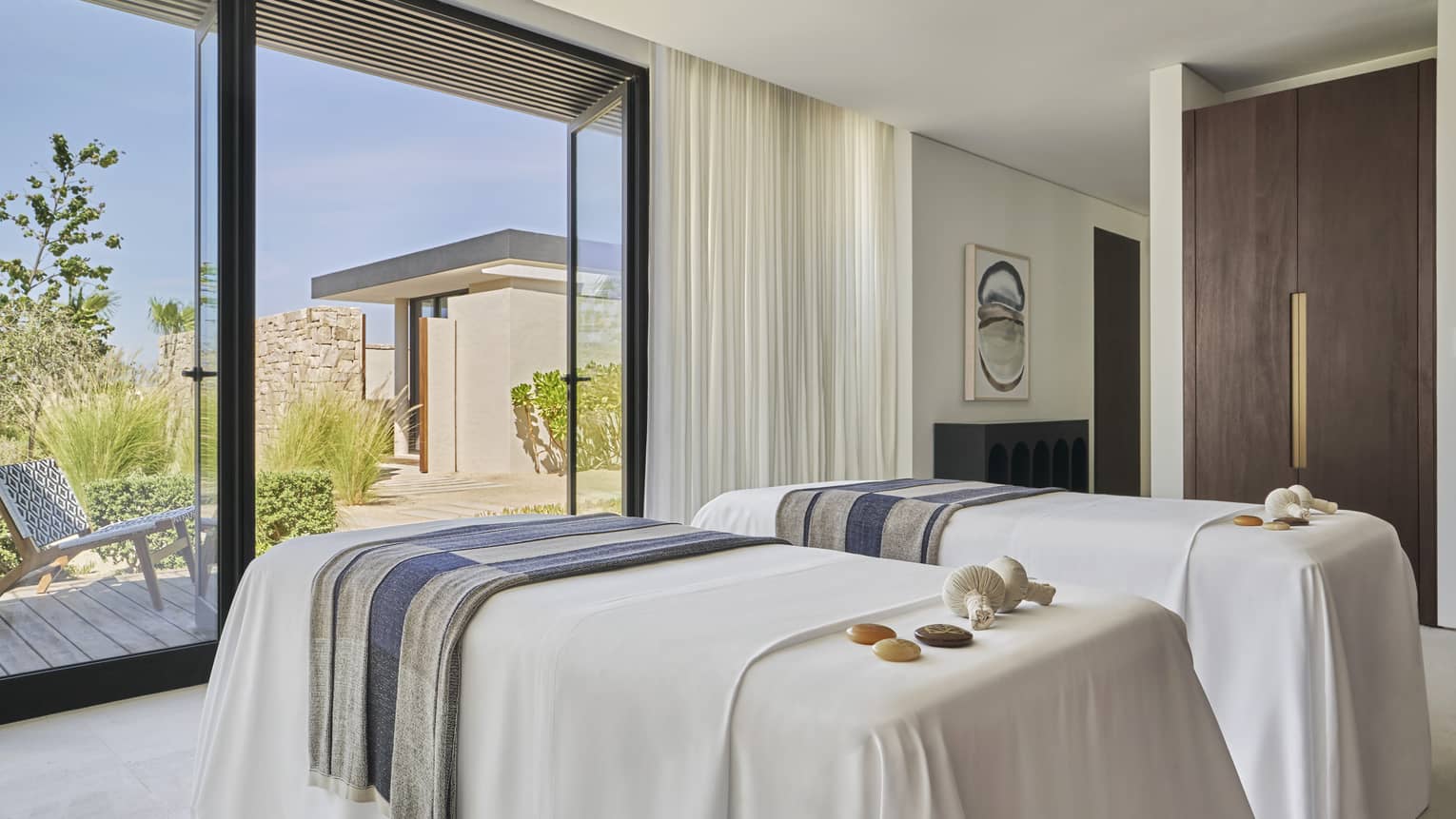 Two massage platforms facing a large window in a well lit room.
