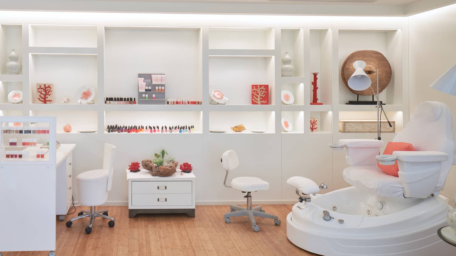 Spa nail bar with manicure station and polish, white wheeled stools, spa pedicure chair, shelving in back