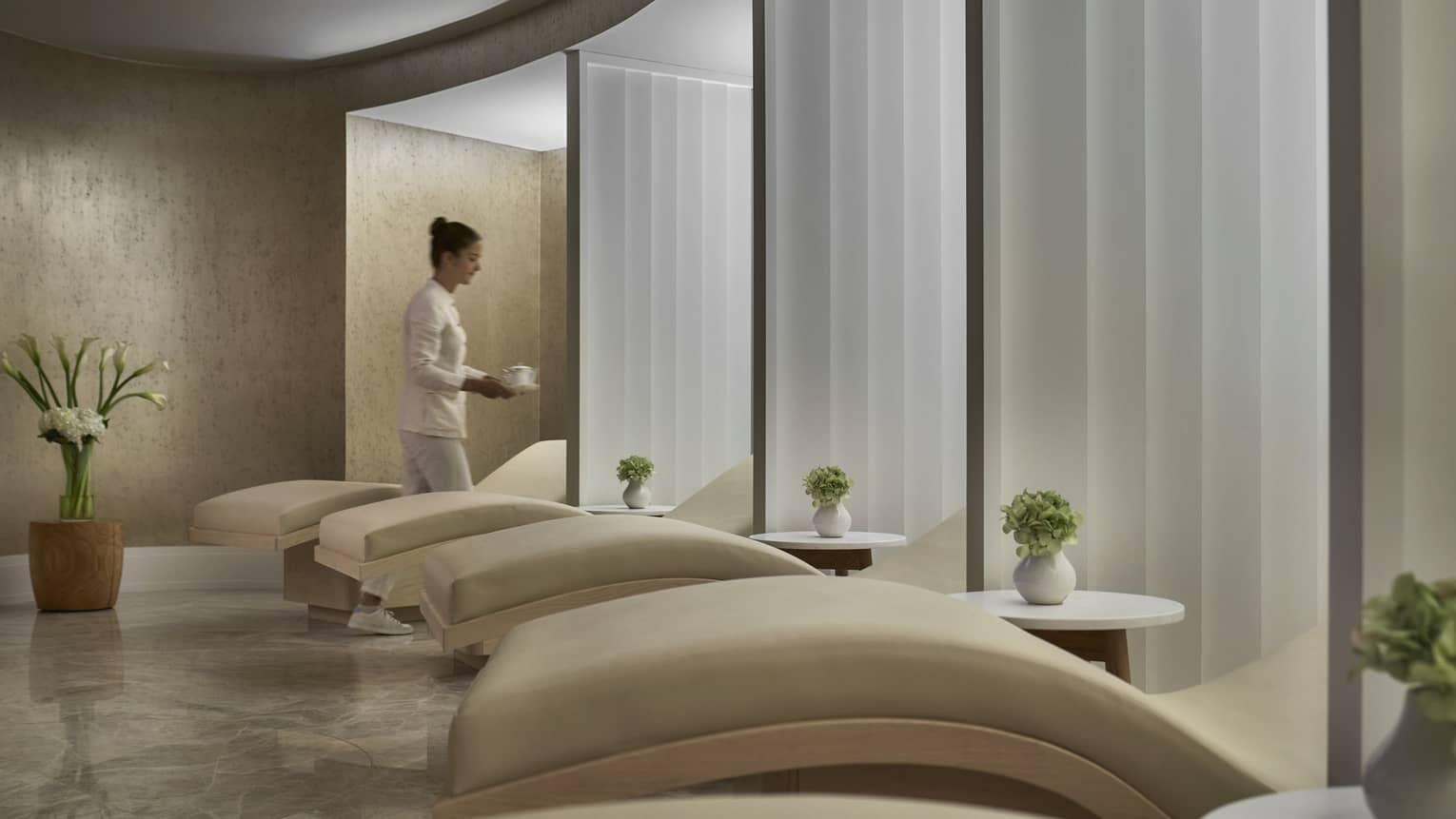 A woman caries cup of coffee in spa relaxation room with five lounge chairs
