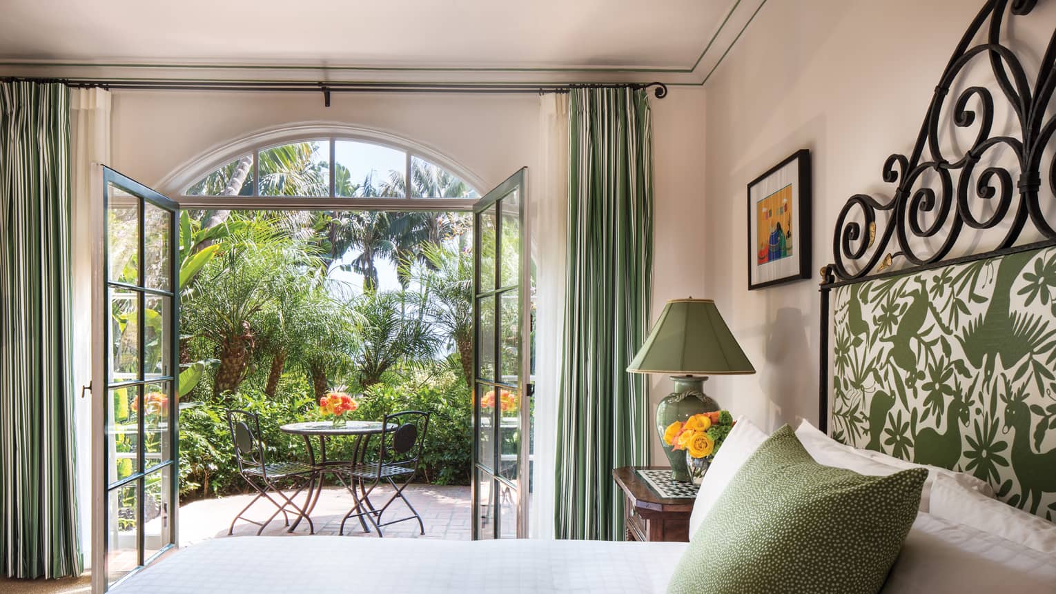 Garden Room open glass doors to sunny balcony, green lamp, pillow, headboard over bed