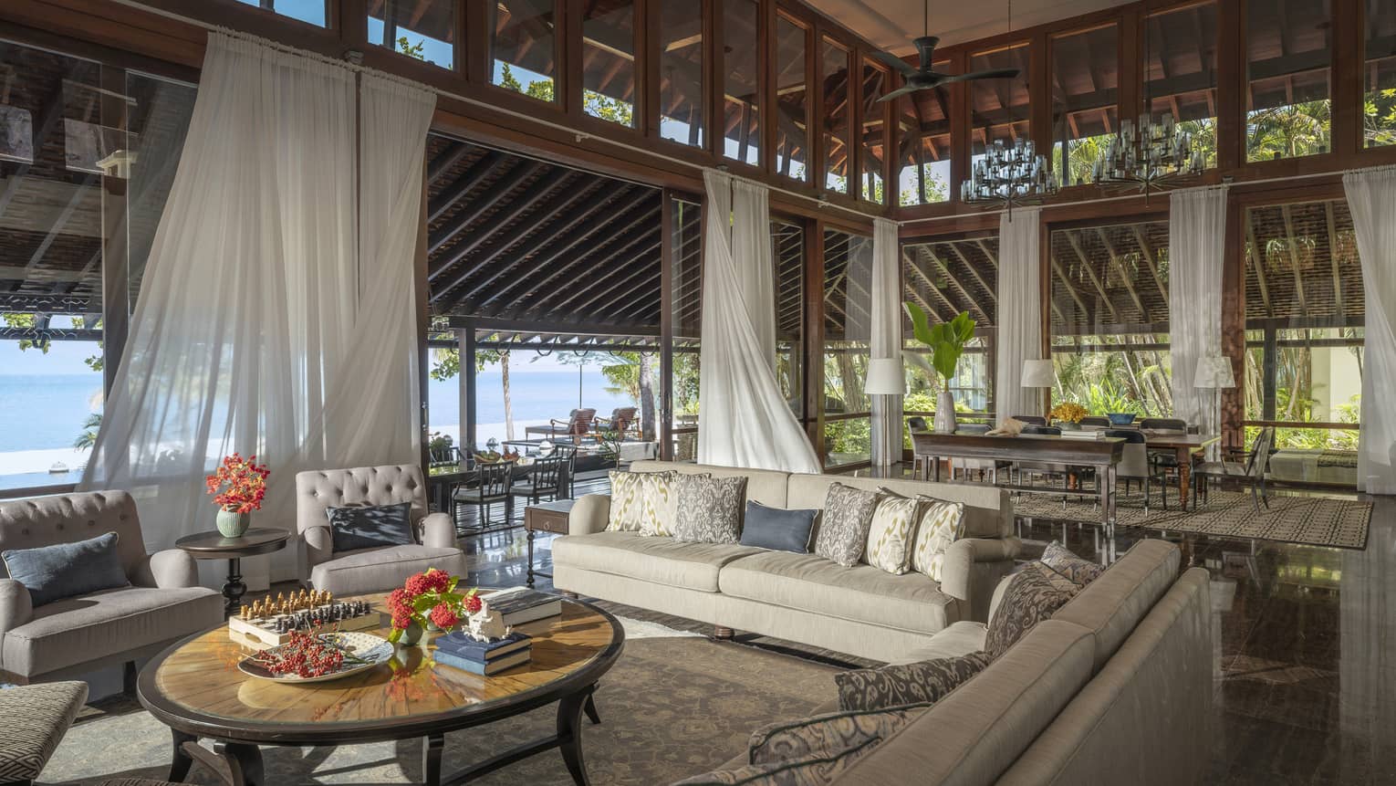 Vast indoor-outdoor living room and great room with high ceilings, flowing white curtains, beach view