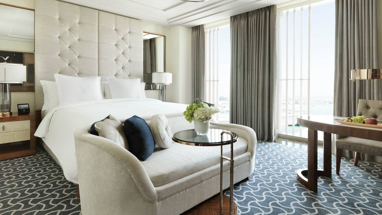 Superior Room plush white sofa with cushions at foot of bed with tall white padded headboard