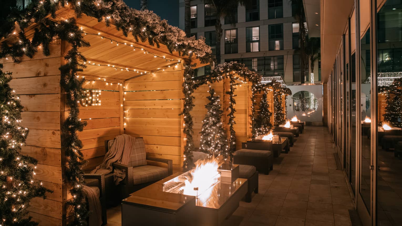 Small seating areas sectioned off and near small fires, with fairy lights hanging above them.