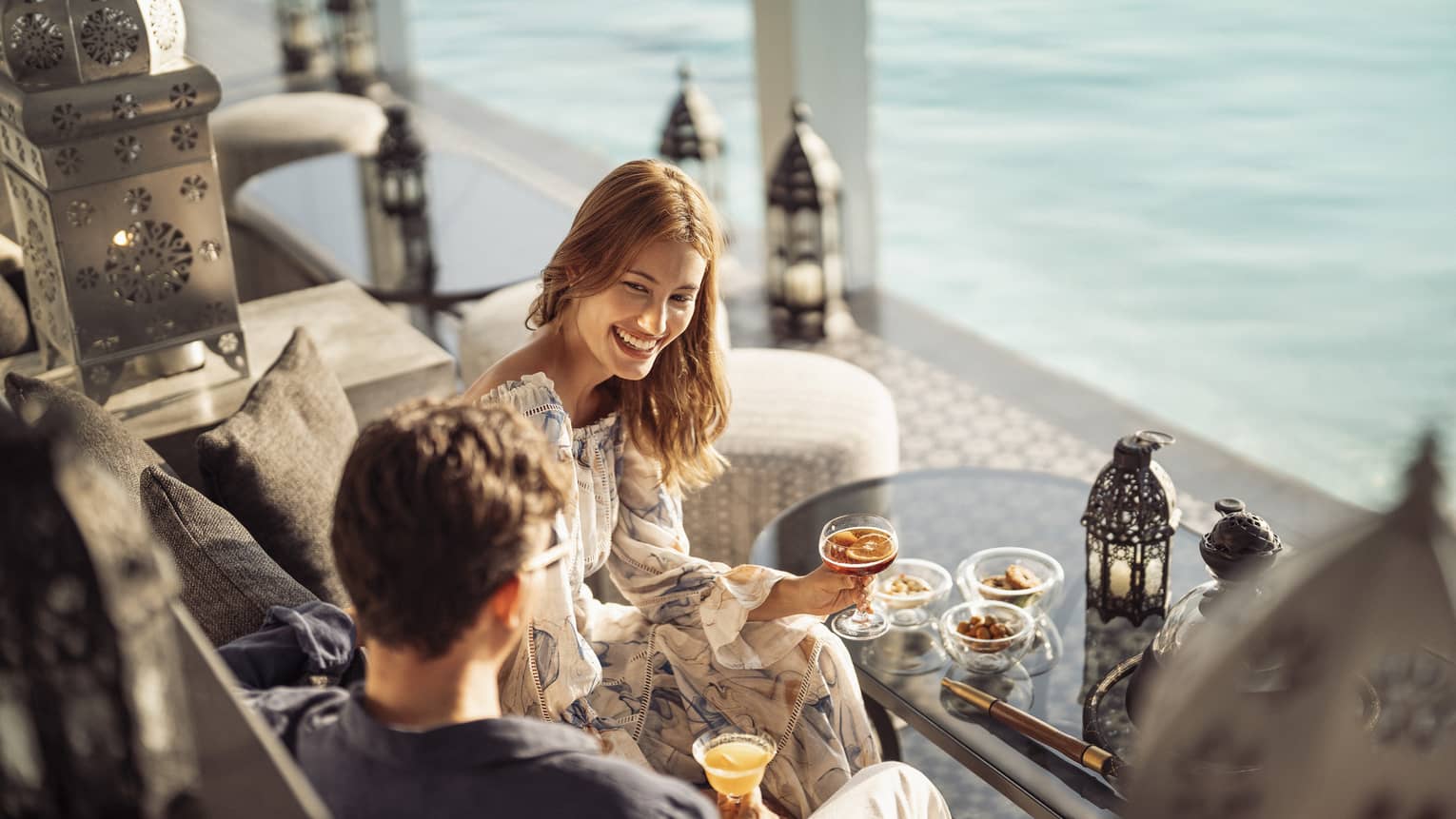 Smiling couple enjoys cocktails on the outdoor terrace of Al Barakat