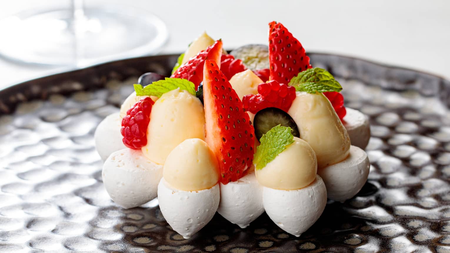 Custard with strawberries on a black plate.