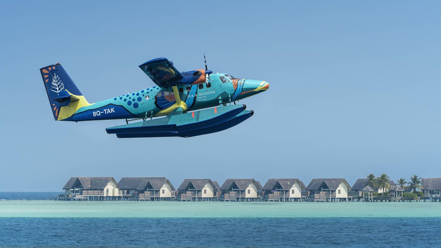 Maldives Sea Plane taking off with water villas and palm trees in the background