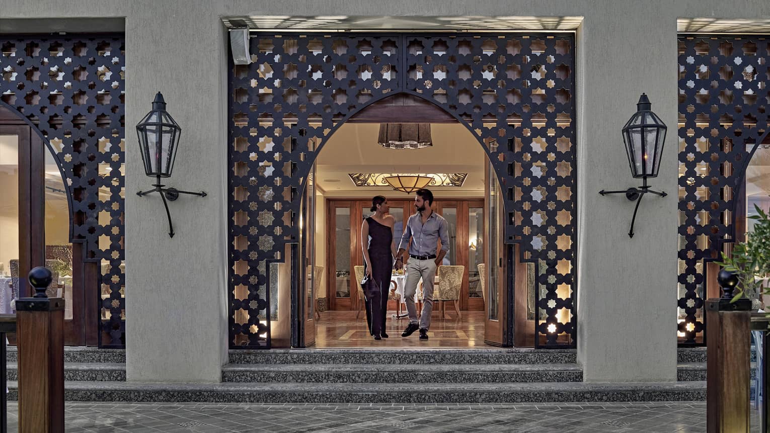 Man and woman walking out of a restaurant with Arabesque detailing around doorway