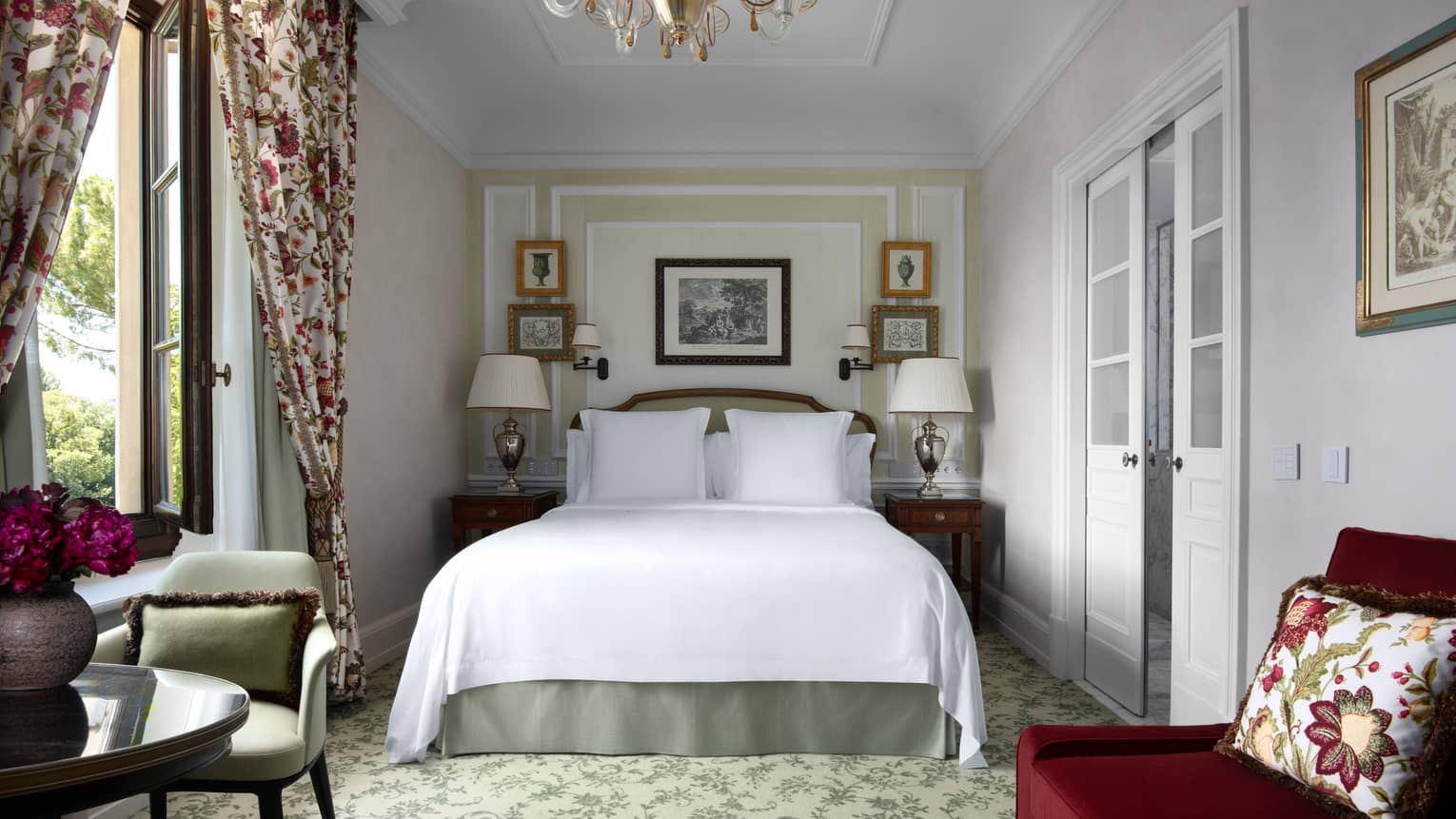 Luxury hotel room with king bed, chandelier, small sofa, and table with chair  at Four Seasons Hotel Florence