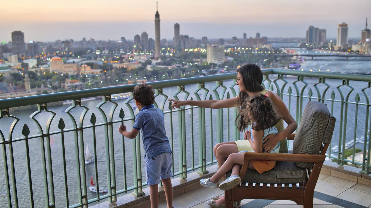 Woman seated with a young girl and beside a young boy standing, overlooking the Nile River and Cairo
