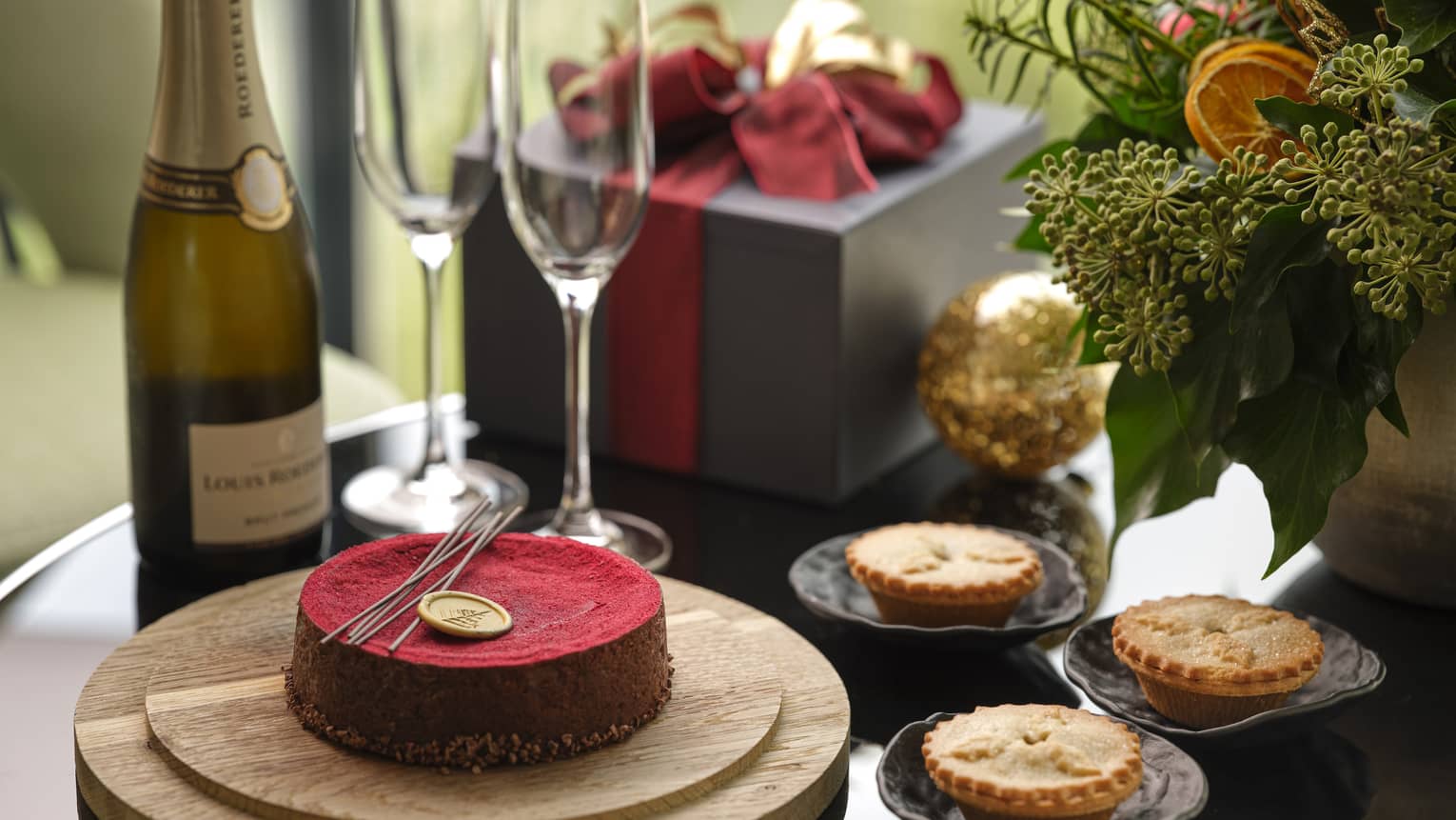 Close-up of holiday cake and three meat pies, plus Champagne bottle and two glasses