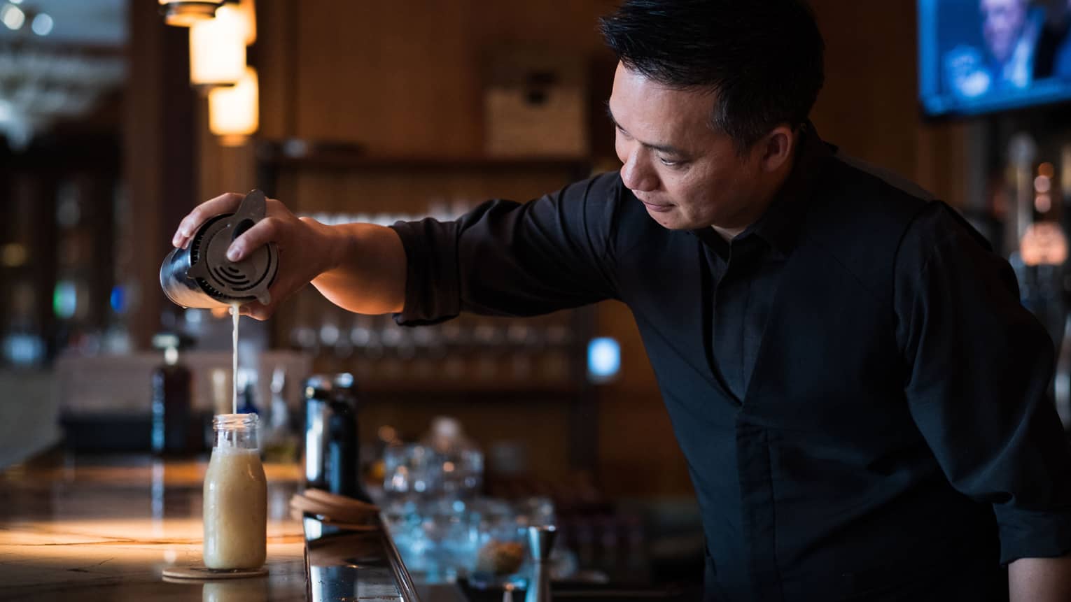 Bartender Alvin Liang pours a frothy liquid into a bottle