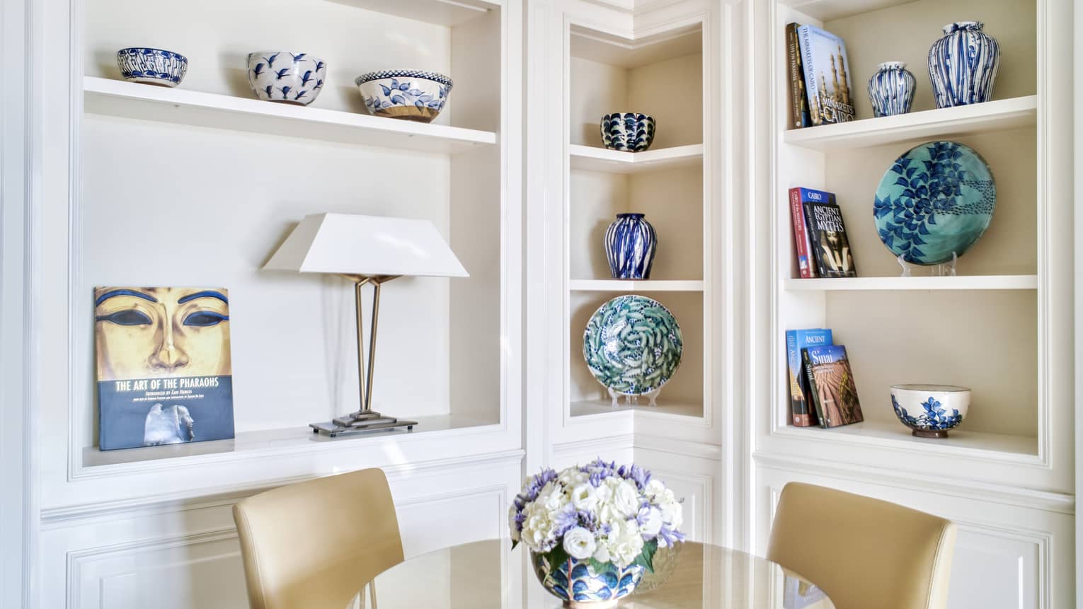Premium Executive Suite dining area with two-seater round glass table, built-in shelves lined with colourful artefacts